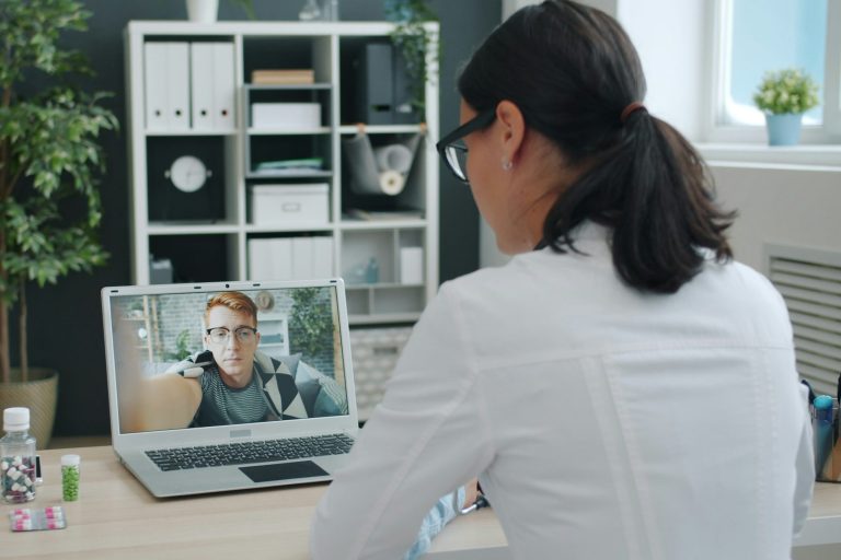 Ein junger Mann und eine Beraterin befinden sich im Videocall am Laptop beim Online-Erstgespräch für die Private Krankenversicherung (PKV).
