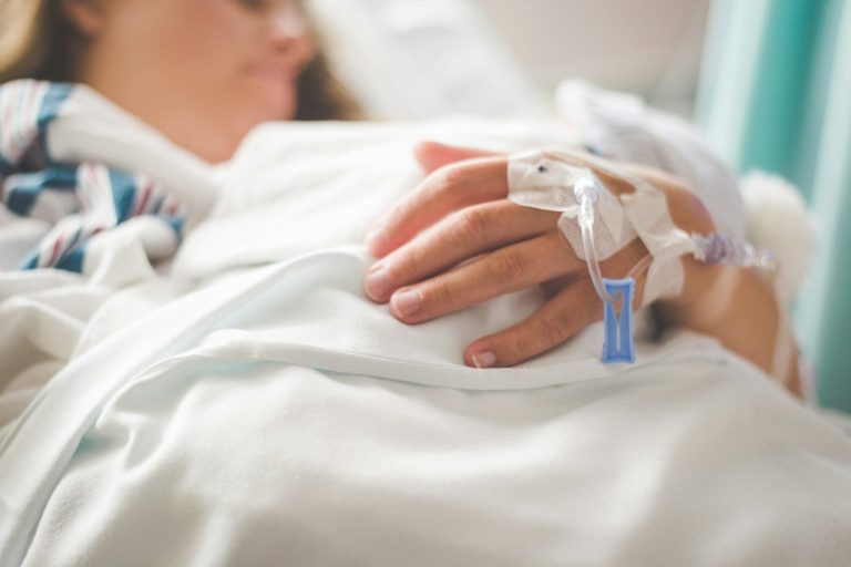 Deine Einkommenssicherung nach der Lohnfortzahlung Eine Frau im Krankenhaus am Infusionstropf symbolisiert die Absicherung durch privates Krankentagegeld für Angestellte bei längerem Ausfall.